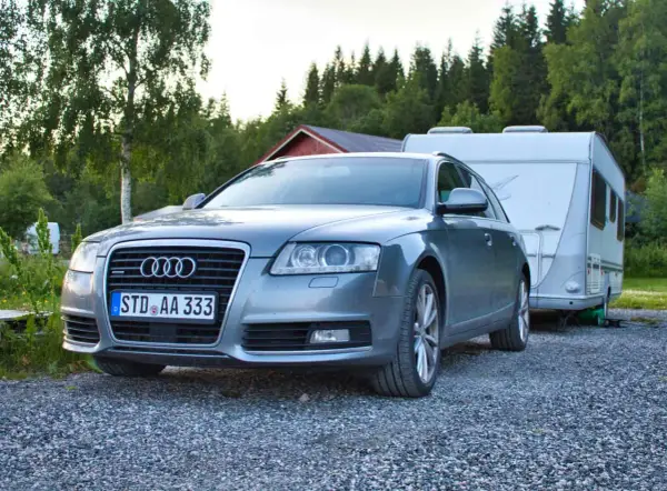 Grauer Audi A6 F4 Kombi mit Wohnwagen im Hintergrund, bereit für den Urlaub.