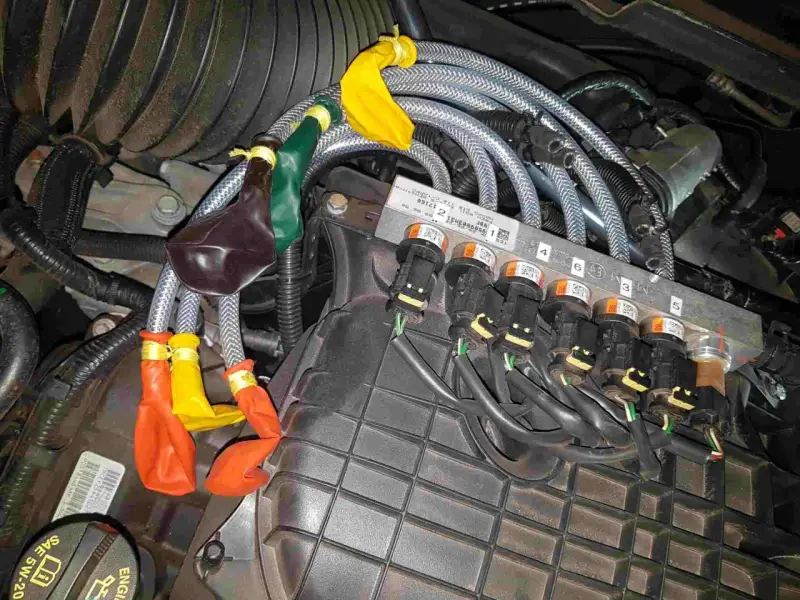 Motorkomponenten mit bunten Ballons an Leitungen. Mögliche Symptome eines defekten Benzinpumpenrelais sind hier zu sehen.
