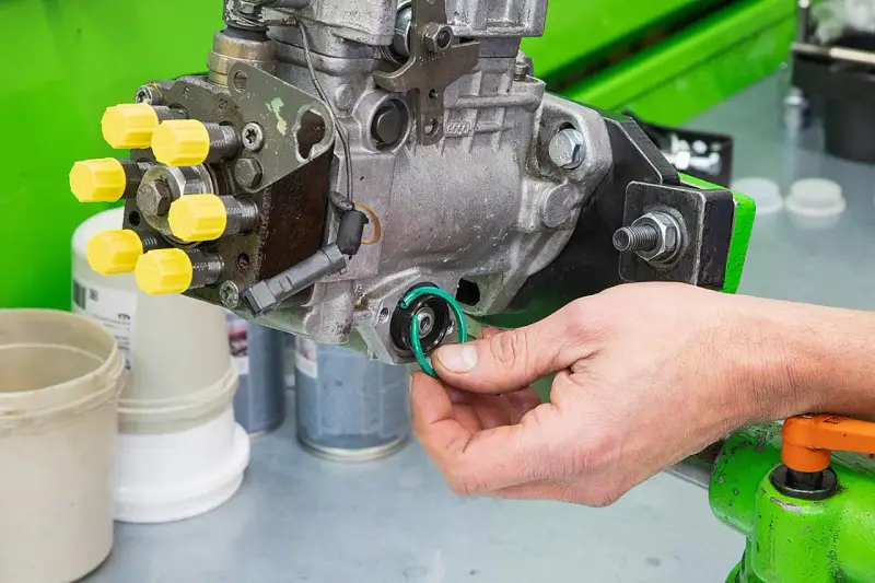 Hand replaces a green O-ring on a Bosch Einspritzpumpe, part of the process to einspritzpumpe reparieren.