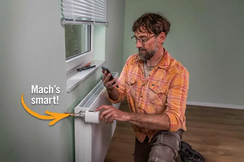 Mann installiert smarten Thermostat am Heizkörper, um Heizkosten zu sparen. "Mach's smart!